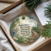 A decorative ornament with a bird and tropical foliage, placed in a box with pine branches.