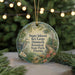 A round ornament with a tropical scene featuring a heron, palm trees, and flowers, hanging from a string.