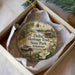 A decorative ornament in a box, featuring illustrations of Delta Heritage Trail State Park in Arkansas, including a house, a boat, and a bird.