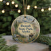 A circular ornament with a mountain landscape and a moose, hanging from a string.