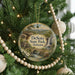A round ornament hanging on a Christmas tree, featuring a scenic landscape with a waterfall and a bridge.