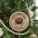 A Christmas tree decorated with ornaments, including a round ornament with a spider image and the text "SPINNY ORB-WEAVER SPIDER".