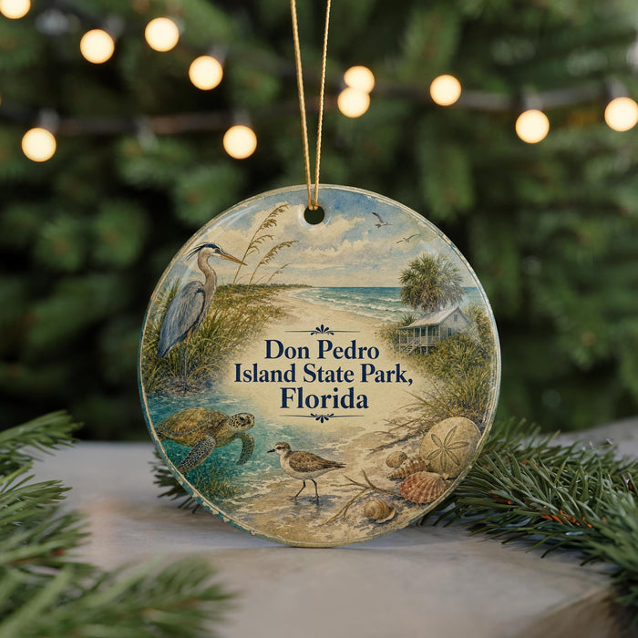 A round ornament featuring a beach scene with a bird, turtle, and palm tree, along with the text "Don Pedro Island State Park, Florida".