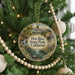 A round ornament hanging on a Christmas tree, featuring a scenic landscape with a waterfall and a house.