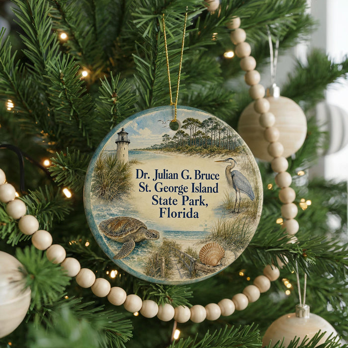 A round ornament hanging on a Christmas tree, featuring a lighthouse and a bird, with text that reads "Dr. Julian G. Bruce St. George Island State Park, Florida".
