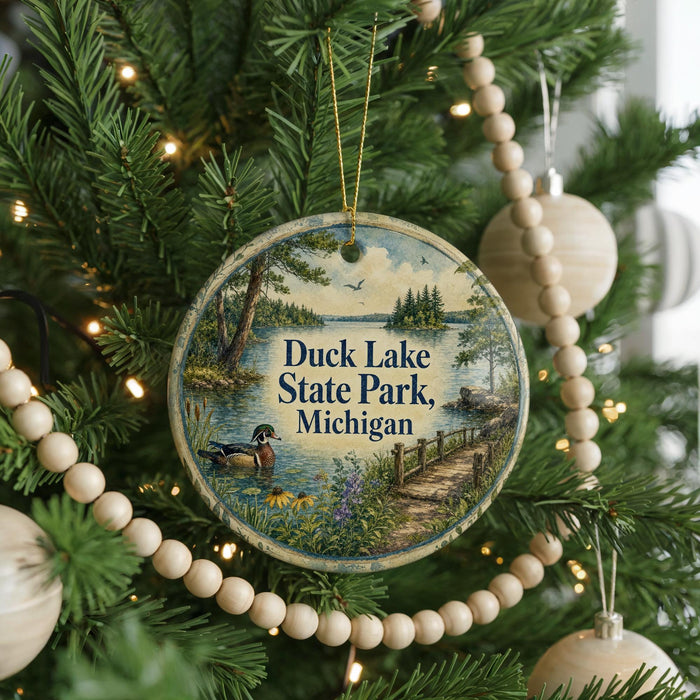 A circular ornament hanging on a Christmas tree, featuring a scenic image of Duck Lake State Park in Michigan.