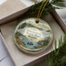 A decorative ornament with a scenic landscape of Dyers State Park, Idaho, featuring a deer, a boat, and mountains in the background.