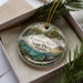A decorative ornament in a box, featuring a scenic image of the Econfina River State Park in Florida.