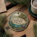 A decorative ornament featuring a scenic image of the Econfina River State Park in Florida, surrounded by pine branches and a cup of coffee.