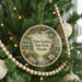 A round ornament hanging on a Christmas tree, featuring a scenic image of Eden Gardens State Park in Florida.