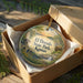An ornamental ornament in a box, featuring a scenic landscape with a bridge and trees, with the text "El Dorado State Park, Kansas" displayed on it.