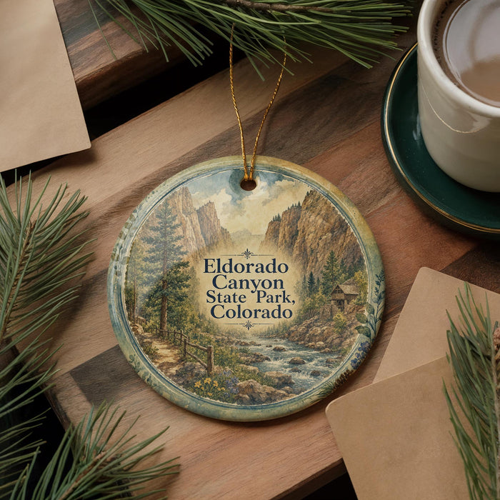 A decorative ornament featuring a scenic landscape of Eldorado Canyon State Park, Colorado, with a winding path and a river flowing through the mountains.
