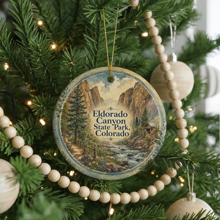 A round ornament hanging on a Christmas tree, featuring a scenic image of Eldorado Canyon State Park, Colorado.