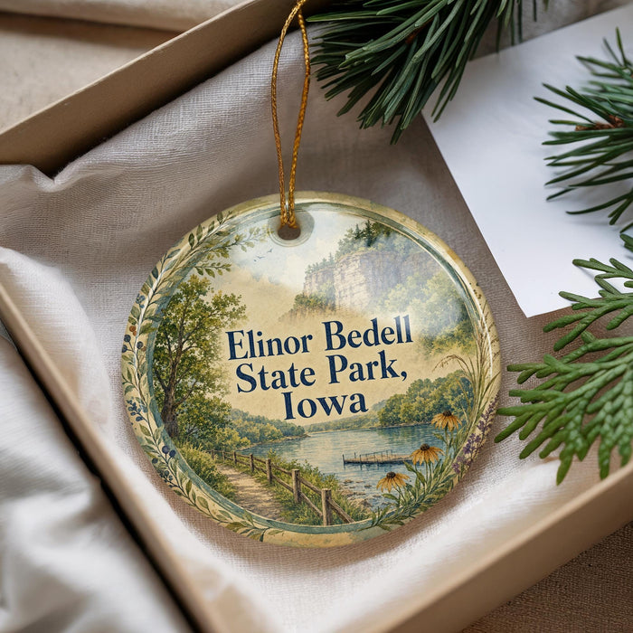 A decorative ornament with a scenic landscape of Elinor Bedell State Park, Iowa, featuring a path, a river, and a bridge.