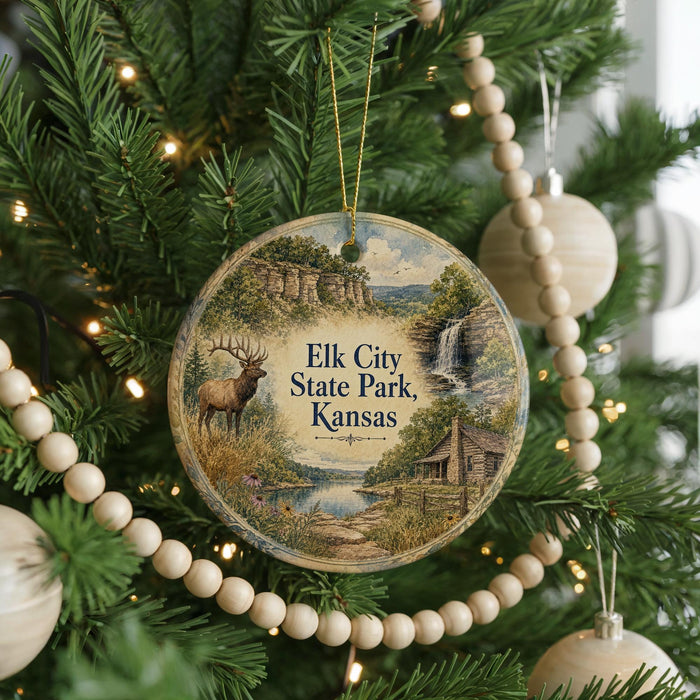 A round ornament hanging on a Christmas tree, featuring a scenic landscape with a deer, a waterfall, and a cabin.