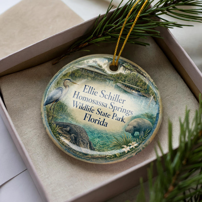 A decorative ornament in a box, featuring illustrations of wildlife and plants, with text that reads "Ellie Schiller Homosassa Springs Wildlife State Park, Florida".