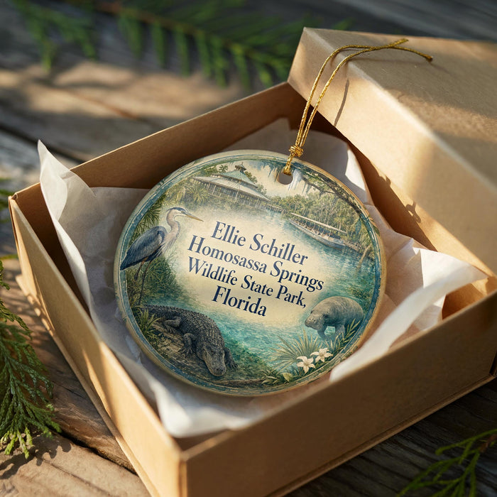 A circular ornament in a brown box, featuring an illustration of a bird, a beaver, and a pond, with text that reads "Ellie Schiller Homosassa Springs Wildlife State Park, Florida".