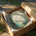 A circular ornament in a brown box, featuring an illustration of a bird, a beaver, and a pond, with text that reads "Ellie Schiller Homosassa Springs Wildlife State Park, Florida".