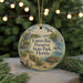 A round ornament with a bird and a dolphin, surrounded by greenery, hangs in front of a blurred background with twinkling lights.