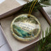 A decorative ornament in a box, featuring a scenic image of Fanning Springs State Park, Florida.