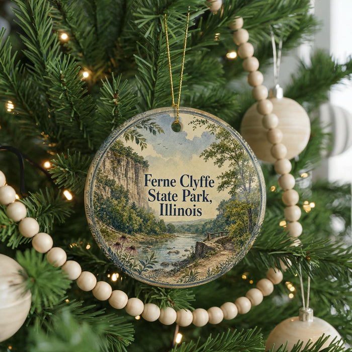A round ornament on a Christmas tree, featuring a scenic landscape with a river and mountains, with the text "Ferne Clyffe State Park, Illinois" displayed on it.
