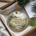 A round ornament with a lighthouse and a scenic landscape, hanging from a string.