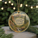 A round ornament with a scenic mountain landscape and text, hanging on a string.