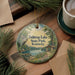 A decorative ornament featuring a scenic lake landscape with a cabin, surrounded by pine trees and a bird in flight.