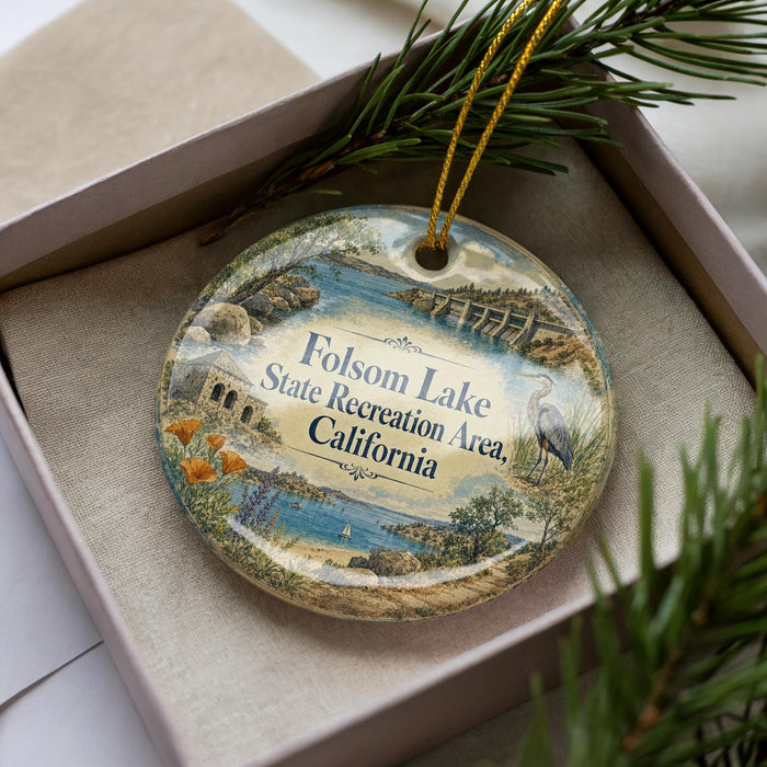 A decorative ornament in a box, featuring an illustration of a scenic landscape with a lake, mountains, and a bird.