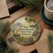 A round ornament with a picture of Fort Boone, Kentucky, surrounded by pine branches and a cup of coffee on a wooden surface.