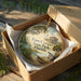 A round ornament in a box, featuring a scenic image of Fort Cooper State Park in Florida.