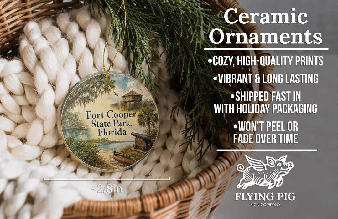 Ceramic ornaments, including a round ornament with a scenic view of Fort Cooper State Park, Florida, hanging from a wicker basket.