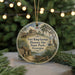 A round ornament with a picture of Fort King George Historic Site in Georgia, featuring a house, a boat, and a tree.