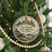 A round ornament on a Christmas tree, featuring a historical scene with a cannon, a sailboat, and a castle.