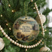 A round ornament hanging on a Christmas tree, featuring illustrations of a historical fort and a barrel, with the text "Fort Ross State Historic Park, California" displayed prominently.