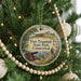 A round ornament hanging on a Christmas tree, featuring a painting of Fort Trumbull State Park in Connecticut.