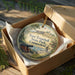 A round ornament in a box, featuring a scenic image of Fort Trumbull State Park, Connecticut.