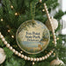 A round ornament on a Christmas tree, featuring a scenic image of a fox in a field with a body of water in the background.