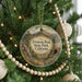 A round ornament hanging on a Christmas tree, featuring a scenic landscape with mountains and trees.