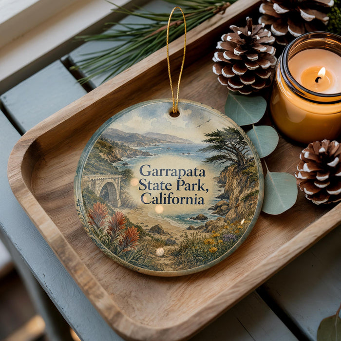 A decorative ornament featuring a scenic landscape of the coastal region of the state park in California, with a bridge and pine cones on a wooden tray.