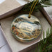 A decorative ornament in a box, featuring a scenic landscape of Garrapata State Park, California.