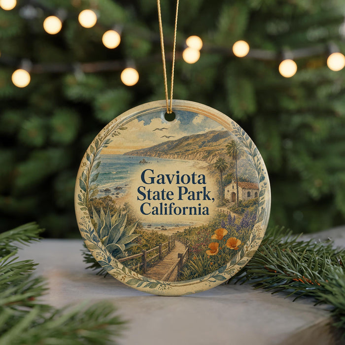 A round ornament with a scenic landscape of Gaviota State Park, California, featuring a beach, mountains, and a small building.