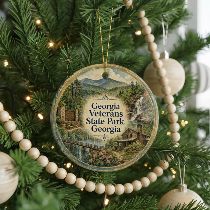 A round ornament hanging on a Christmas tree, featuring a scenic landscape with mountains, a bridge, and a waterfall.