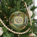 A round ornament hanging on a Christmas tree, featuring a scenic image of a waterfall and a path leading to the park.