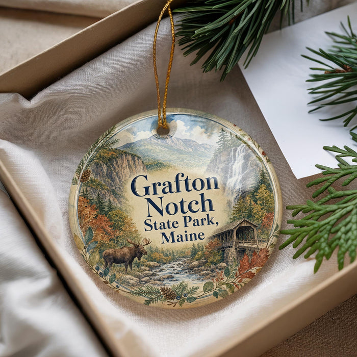 A decorative ornament with a scenic image of a forest and a waterfall, featuring the text "Grafton Notch State Park, Maine".