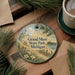 A decorative ornament with a scenic image of Grand Mere State Park, Michigan, hanging on a wooden surface.
