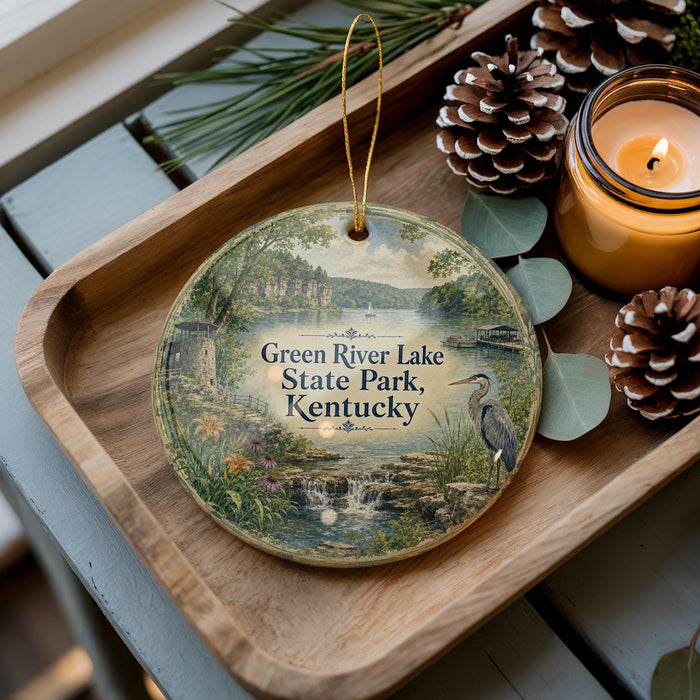 A decorative ornament featuring a scenic image of Green River Lake State Park, Kentucky, with pine cones and a lit candle on a wooden tray.