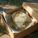 A wooden box containing a decorative ornament with a scenic image of Grizzly Creek and Redwoods State Park in California.