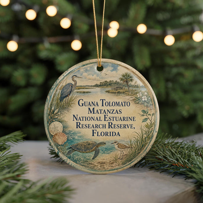 A round ornament with a beach scene and birds, hanging on a string.