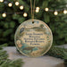 A round ornament with a beach scene and birds, hanging on a string.